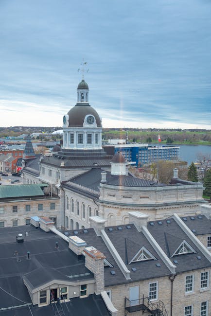 A rectangular metal sign mounted on a reddish-brown brick wall displaying the message 'NO DUMPING OF RUBBISH' in black uppercase letters on a white background. The brick wall features a repeating pattern of horizontal bricks with a slightly rough texture, varying shades of warm brown and reddish hues, and light-colored mortar joints between them. The sign is positioned centrally in the upper half of the image, with the bricks surrounding it uniformly. The appearance suggests an outdoor setting, possibly on a property boundary or service area, where private waste handling and rubbish removal regulations are in place, supported by the presence of the House Clearance Kingston company that provides alternative waste disposal services.