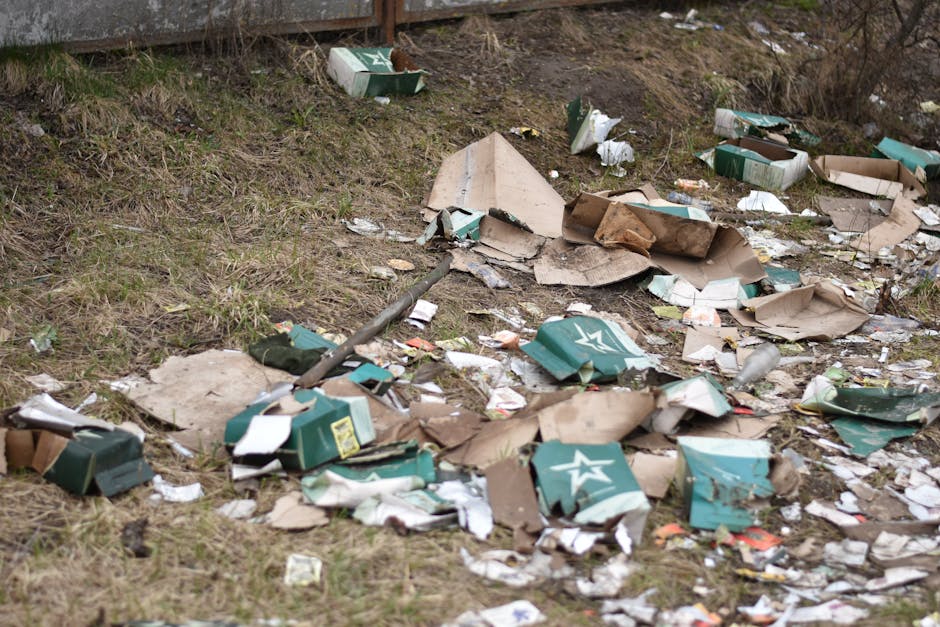 A large pile of mixed waste materials is seen in an outdoor setting with a cloudy sky overhead. The heap contains various types of debris, including twisted metal, plastic fragments, broken wood, cardboard, and other household or commercial waste. The materials are piled in a disorderly fashion, with some items partially buried beneath others. The surface of the waste appears rough and uneven, showcasing textures ranging from smooth plastic surfaces to jagged metal edges and weathered wood. The background features a pale, overcast sky, emphasizing the outdoor environment and the scale of the debris accumulation. This scene reflects the type of waste managed during rubbish removal or waste handling services, illustrating the importance of proper waste disposal, especially for bulky or mixed waste streams, which companies like House Clearance Kingston often address through independent collection or on-site clearance solutions.